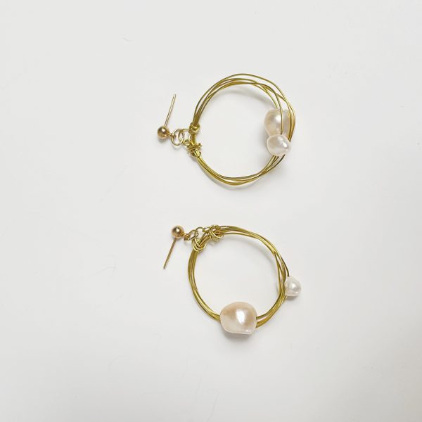 Pendientes de aro hechos a mano en color dorado con detalle de perlas cultivadas.