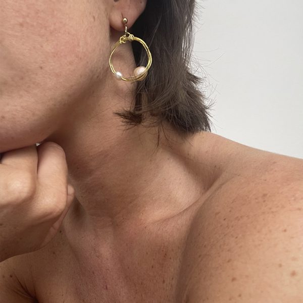 Detalle pendientes de aro pequeños en color dorado con dos perlas cultivadas hechos a mano.